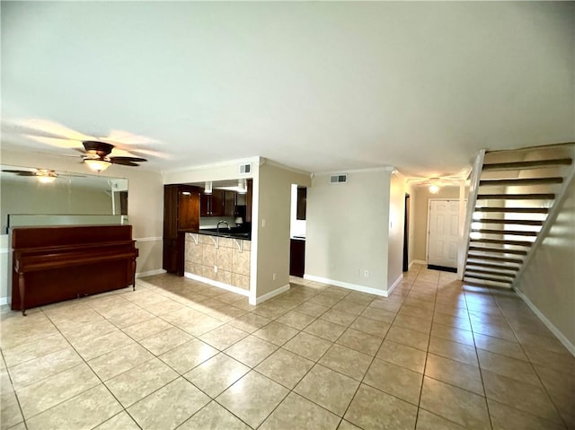 unfurnished living room with ceiling fan, light tile patterned flooring, crown molding, and sink