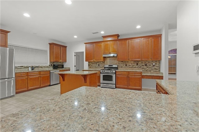 kitchen with a breakfast bar area, stainless steel appliances, light stone countertops, light tile patterned floors, and tasteful backsplash