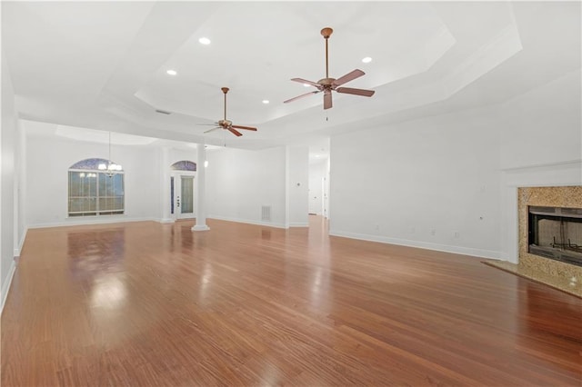 unfurnished living room featuring light hardwood / wood-style flooring, a tray ceiling, and a fireplace