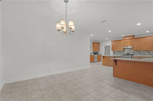 kitchen featuring light stone countertops, appliances with stainless steel finishes, pendant lighting, a breakfast bar, and an inviting chandelier