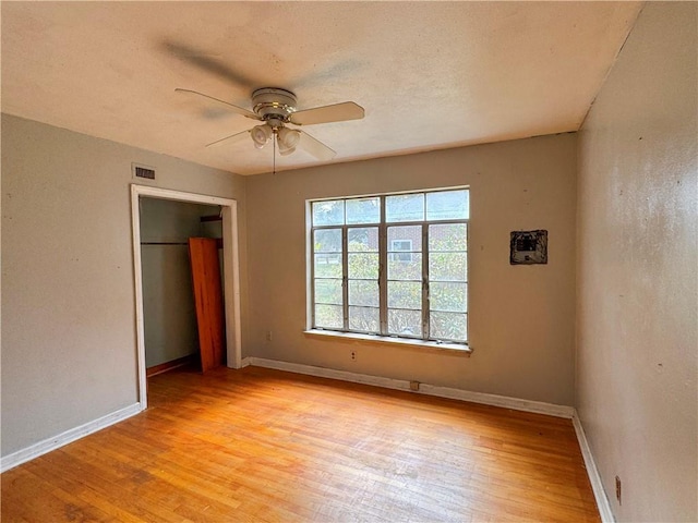 unfurnished bedroom featuring ceiling fan, light wood-type flooring, visible vents, and baseboards