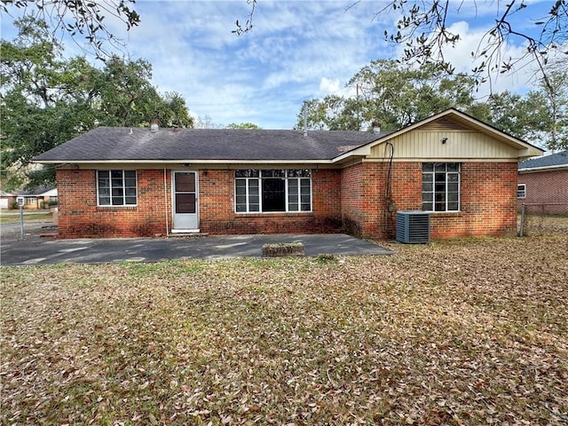 view of front of property featuring brick siding, a patio, and central AC