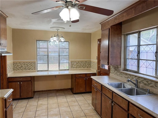 kitchen with light tile patterned floors, tasteful backsplash, a sink, light countertops, and built in desk