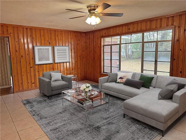 living area featuring crown molding, ceiling fan, wood walls, and light tile patterned floors