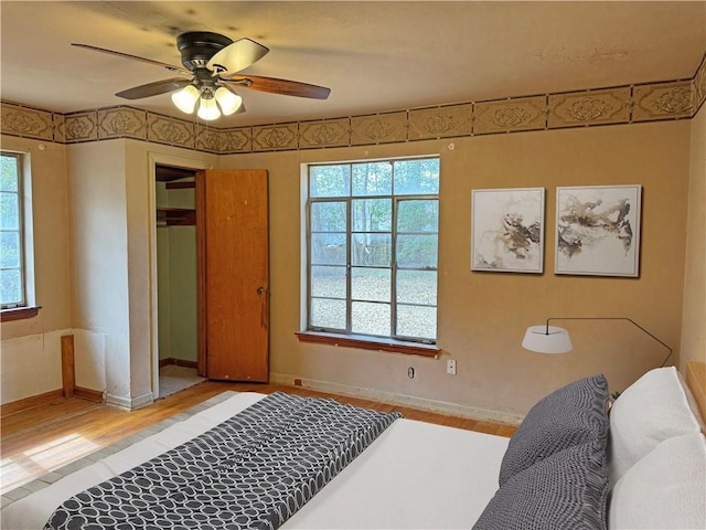 bedroom featuring ceiling fan, wood finished floors, and baseboards