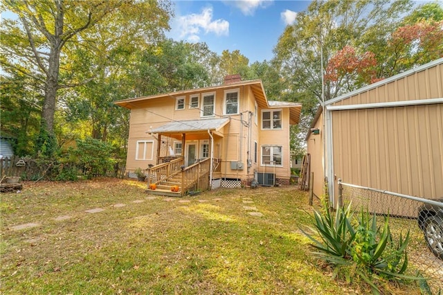 rear view of house featuring central AC and a lawn