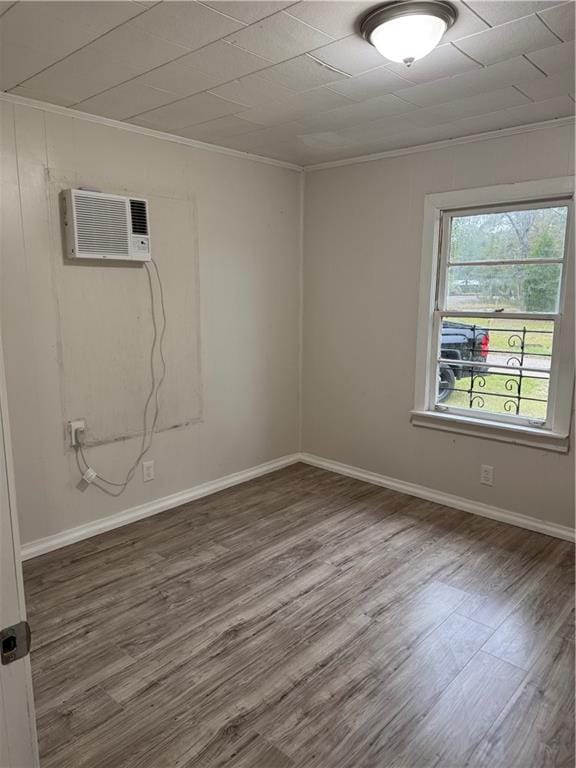 empty room with ornamental molding, a wall mounted air conditioner, and hardwood / wood-style flooring