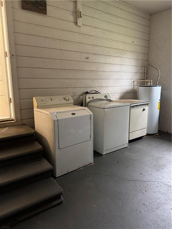 clothes washing area with water heater, wooden walls, and washing machine and clothes dryer