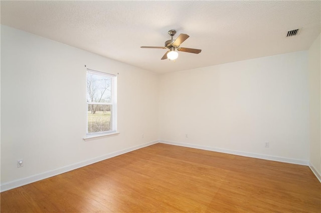 unfurnished room with visible vents, a ceiling fan, a textured ceiling, light wood-style floors, and baseboards