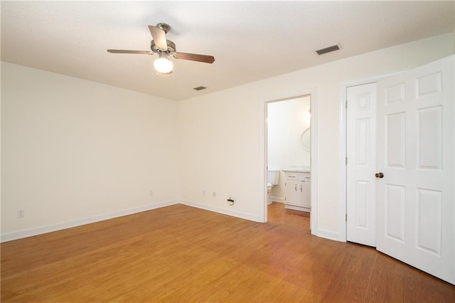 unfurnished bedroom featuring visible vents, a ceiling fan, connected bathroom, light wood-style floors, and baseboards