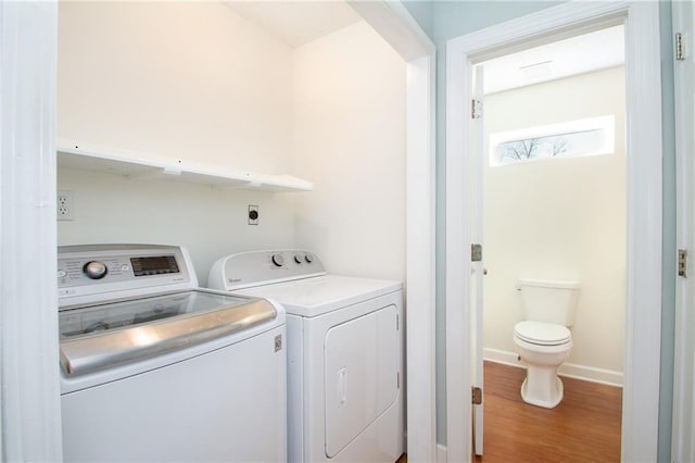 clothes washing area featuring baseboards, separate washer and dryer, wood finished floors, and laundry area