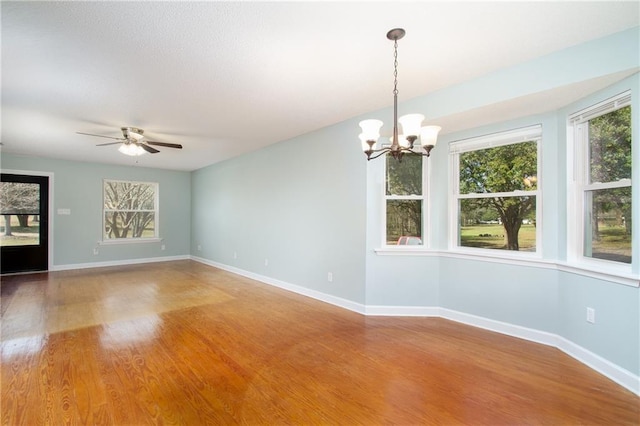 unfurnished room with baseboards, wood finished floors, and ceiling fan with notable chandelier