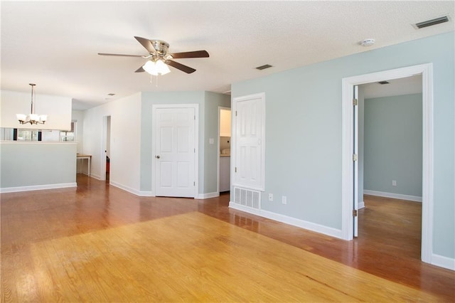 unfurnished room with visible vents, baseboards, light wood-type flooring, ceiling fan with notable chandelier, and a textured ceiling