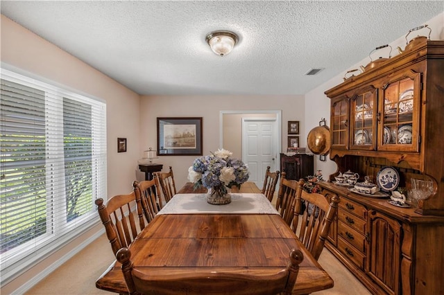 dining room with light colored carpet and a textured ceiling