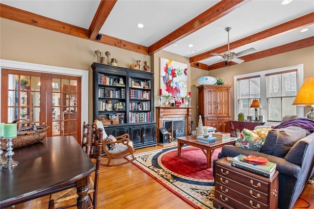 living room featuring hardwood / wood-style floors, beamed ceiling, and ceiling fan