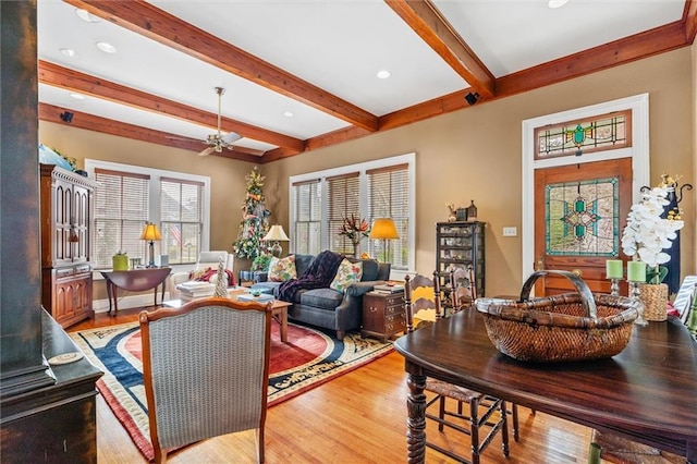 living room featuring light hardwood / wood-style flooring, beam ceiling, and ceiling fan