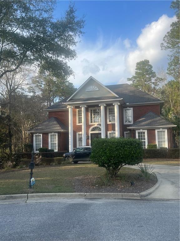 greek revival house with a front lawn and driveway