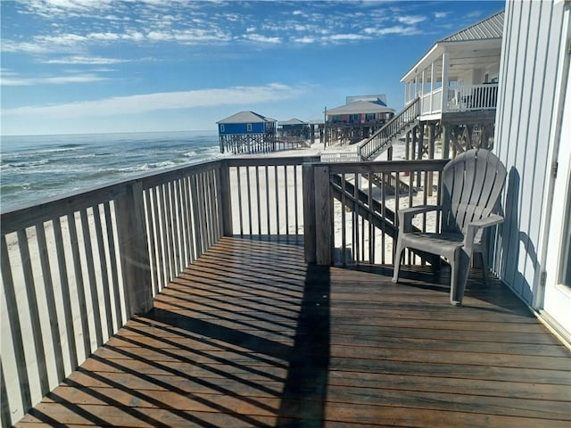 wooden deck with a water view and a view of the beach