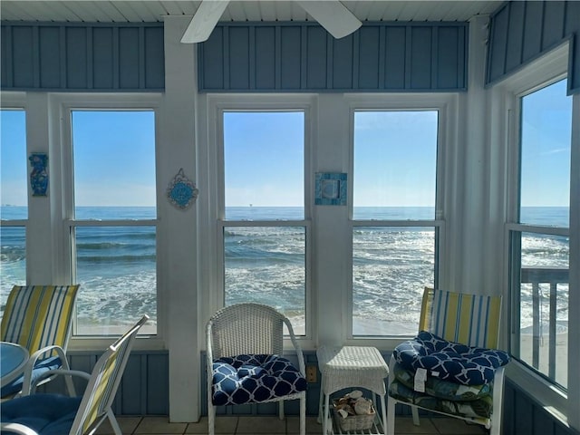 sunroom / solarium with a view of the beach, a water view, plenty of natural light, and ceiling fan