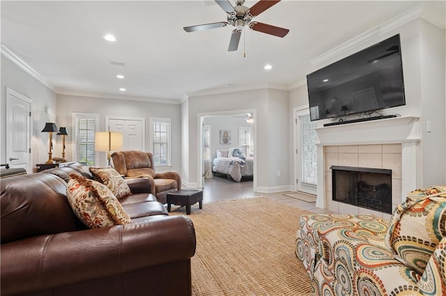 living room featuring ornamental molding, a tiled fireplace, and ceiling fan