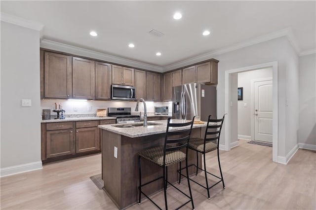 kitchen featuring light stone countertops, stainless steel appliances, light hardwood / wood-style floors, and sink