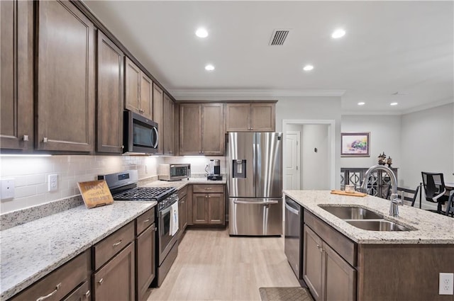 kitchen featuring light wood-type flooring, sink, a center island with sink, appliances with stainless steel finishes, and light stone countertops