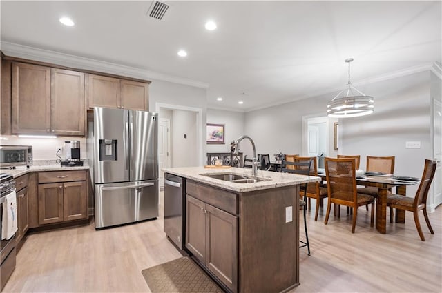 kitchen with sink, a notable chandelier, a center island with sink, appliances with stainless steel finishes, and decorative light fixtures