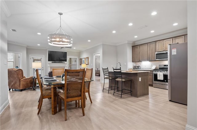 dining area with an inviting chandelier, light wood-type flooring, and crown molding