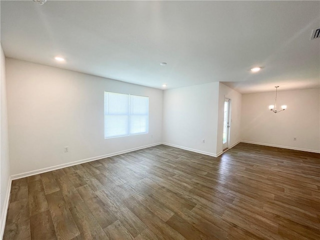 unfurnished room featuring a chandelier and dark wood-type flooring