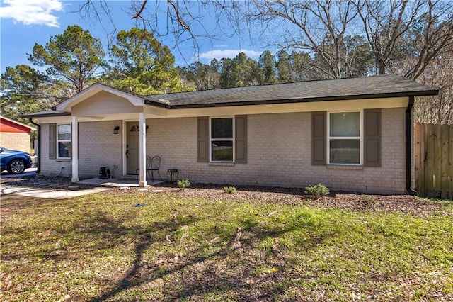 ranch-style home with brick siding, a front lawn, and fence