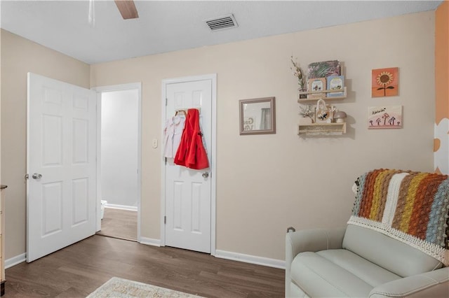 sitting room featuring baseboards, visible vents, ceiling fan, and wood finished floors