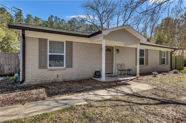 ranch-style house featuring brick siding and fence