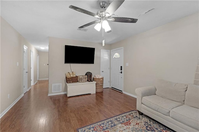 living room with a ceiling fan, visible vents, and dark wood-style flooring