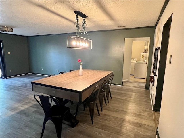 dining room featuring hardwood / wood-style flooring, ornamental molding, washing machine and dryer, and a textured ceiling