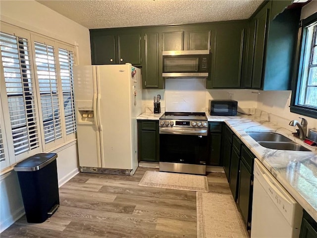 kitchen featuring sink, light hardwood / wood-style flooring, stainless steel appliances, a textured ceiling, and green cabinetry