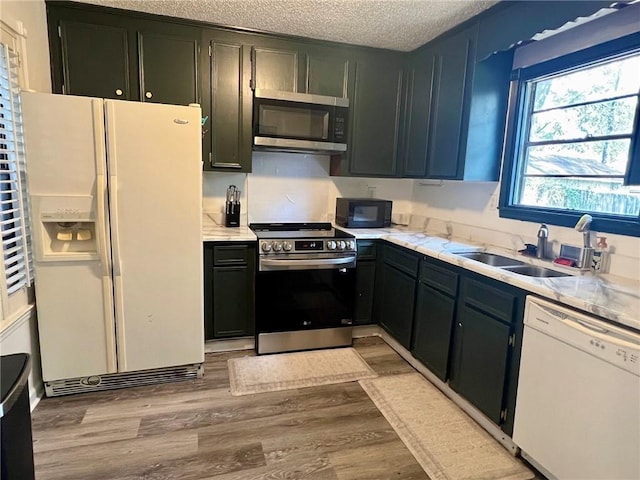 kitchen with sink, stainless steel appliances, a textured ceiling, and light wood-type flooring