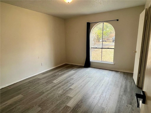 empty room with dark hardwood / wood-style flooring and a textured ceiling