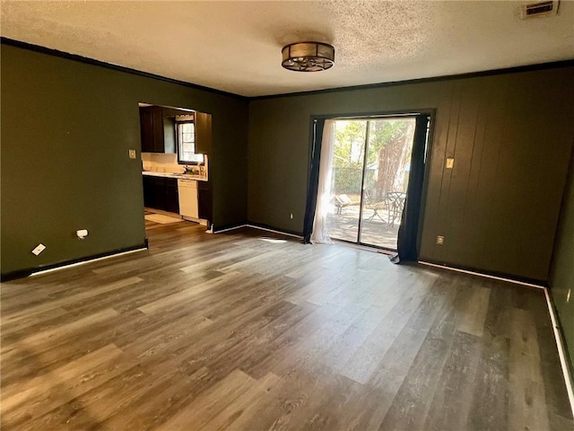 unfurnished room featuring crown molding, wood-type flooring, and a textured ceiling