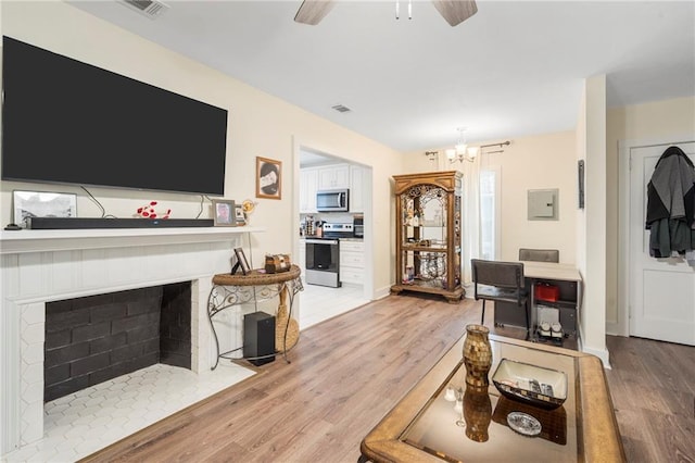 living room with ceiling fan with notable chandelier and light wood-type flooring