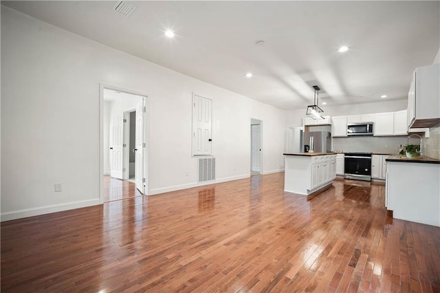 4 Straight St, Mobile, AL 36604 - kitchen with decorative backsplash, dark countertops, a kitchen island, stainless steel appliances, and light wood-type flooring