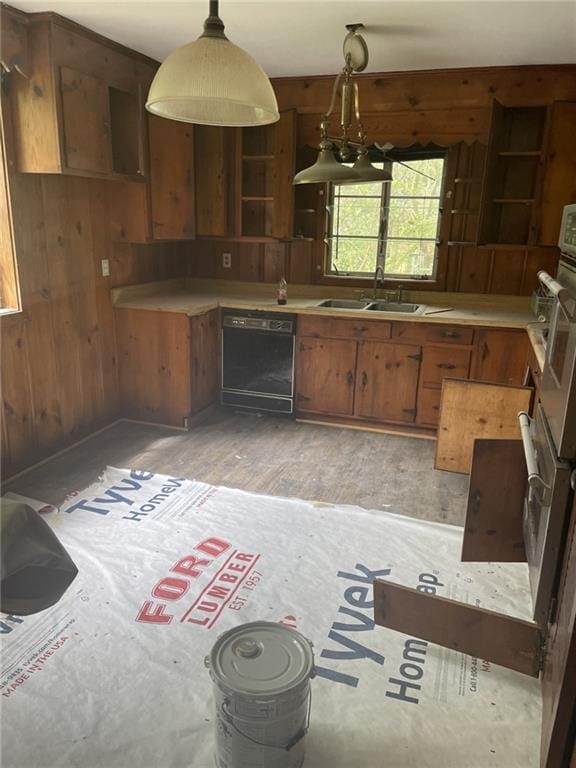 2065 Magnolia Ln, Mobile, AL 36605 - kitchen with black dishwasher, a sink, wooden walls, brown cabinets, and light countertops