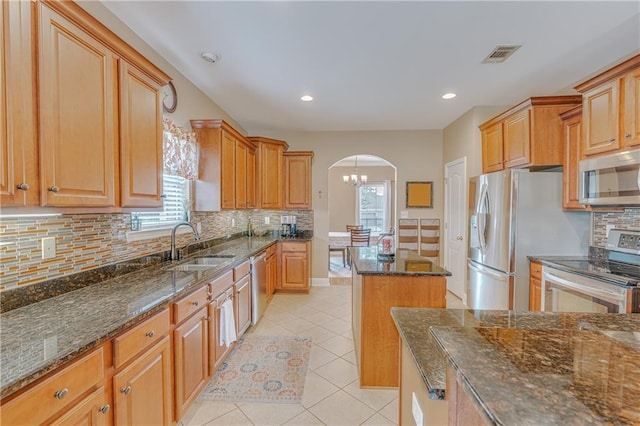 10808 Legacy Ln, Mobile, AL 36608 - kitchen featuring stainless steel appliances, arched walkways, tasteful backsplash, light tile patterned floors, and dark stone countertops