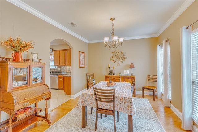 10808 Legacy Ln, Mobile, AL 36608 - dining room featuring arched walkways, a chandelier, crown molding, and light wood-style floors