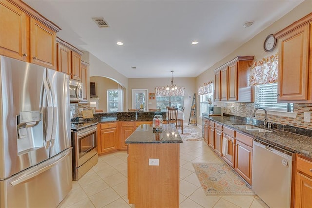 10808 Legacy Ln, Mobile, AL 36608 - kitchen featuring appliances with stainless steel finishes, a chandelier, a peninsula, tasteful backsplash, and arched walkways