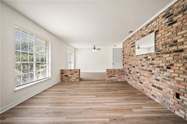 interior space with ceiling fan, brick wall, and light hardwood / wood-style floors