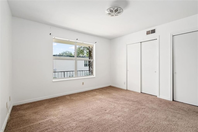 unfurnished bedroom featuring carpet floors and multiple closets