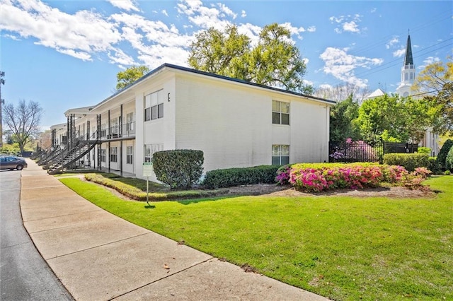 view of side of property with a lawn and a balcony