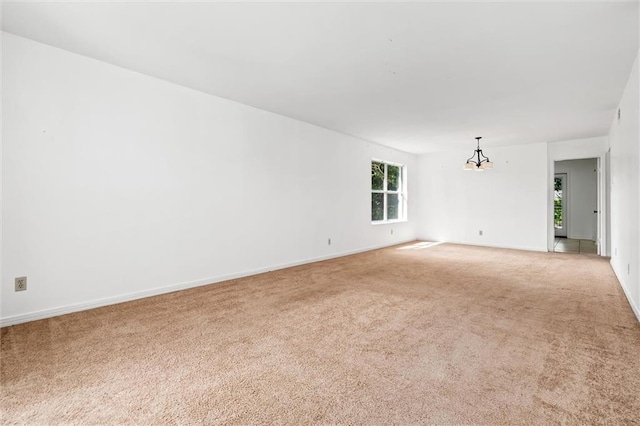 carpeted spare room with a chandelier