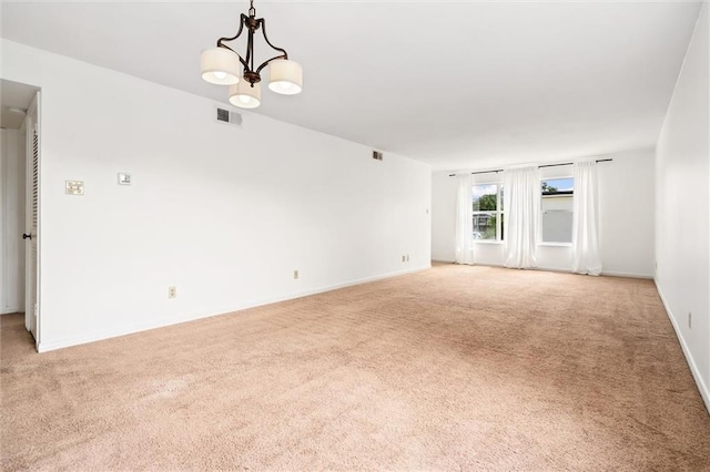 carpeted spare room featuring a chandelier