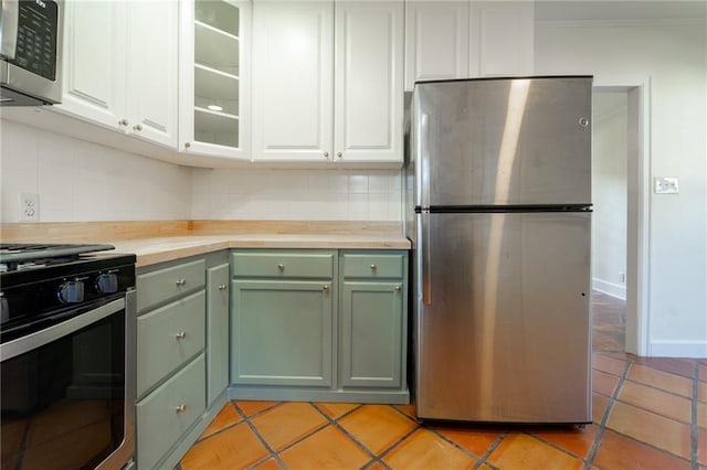 kitchen with butcher block counters, stainless steel appliances, white cabinets, backsplash, and light tile patterned flooring